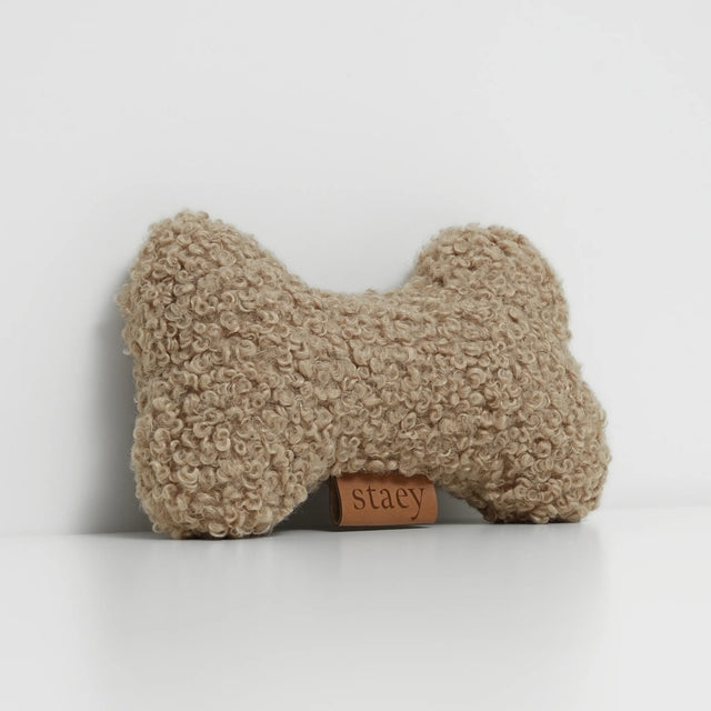 Jouet pour chien en tissu bouclé couleur sable, forme os, sur fond blanc