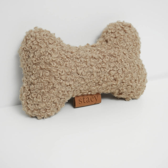 Jouet pour chien en tissu bouclé couleur sable, forme os, sur fond neutre