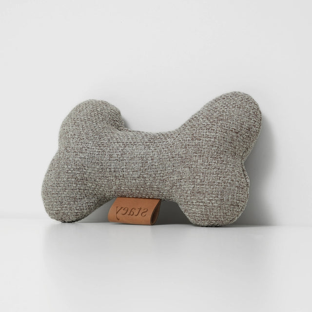 Jouet pour chien en tissu gris corde, forme os, posé sur fond neutre