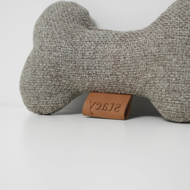 Jouet pour chien en tissu gris corde, forme os, posé sur fond blanc