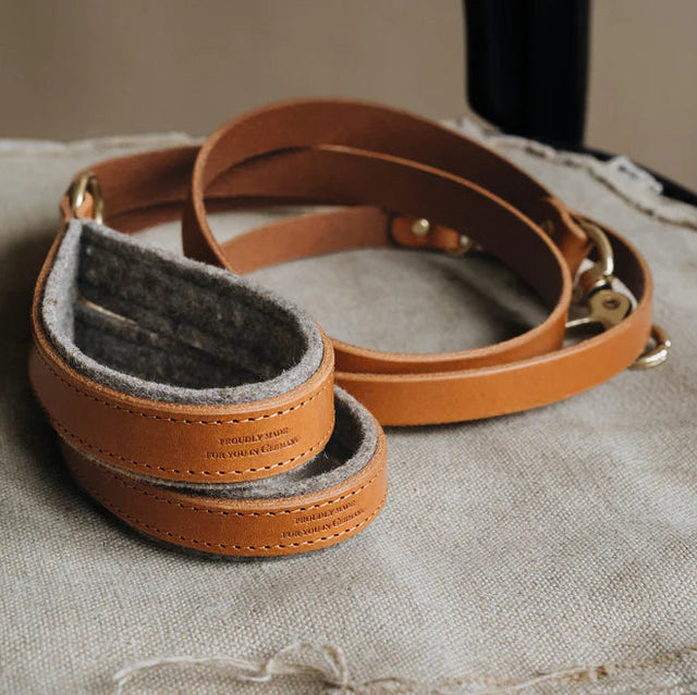 Laisse courte en cuir beige posée sur une chaise