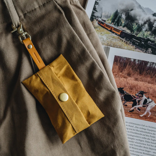 Porte-sacs à crottes moutarde accroché à un pantalon