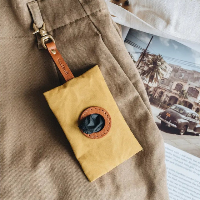 Porte-sacs à crottes moutarde accroché à un pantalon
